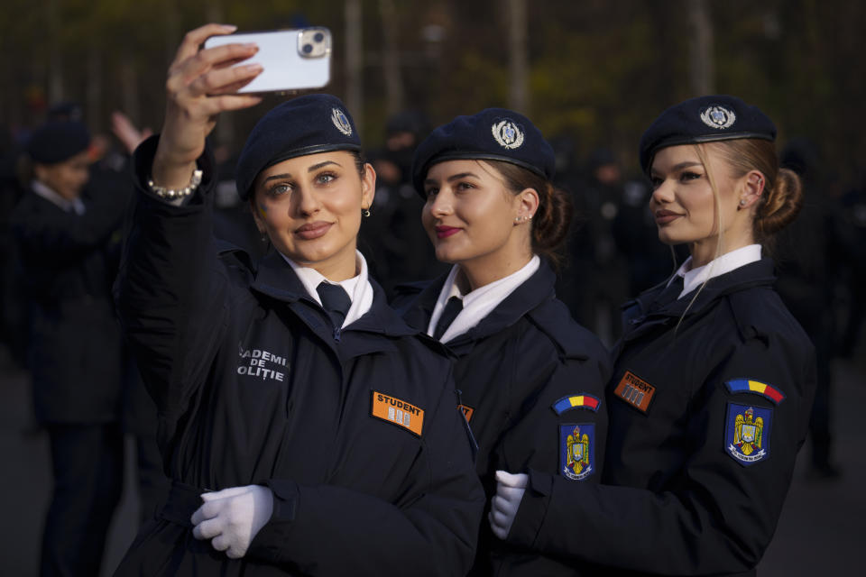 Police academy students pose for a selfie picture before the National Day parade in Bucharest, Romania, Friday, Dec. 1, 2023. Tens of thousands of people turned out in Romania's capital on Friday to watch a military parade that included troops from NATO allies to mark the country's National Day. (AP Photo/Vadim Ghirda)