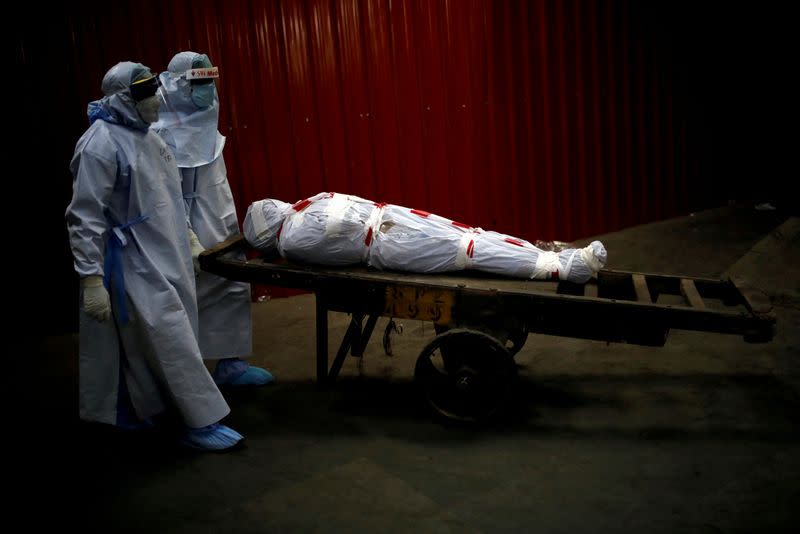 FILE PHOTO: Health workers carry the body of a man who died due to the coronavirus disease in New Delhi