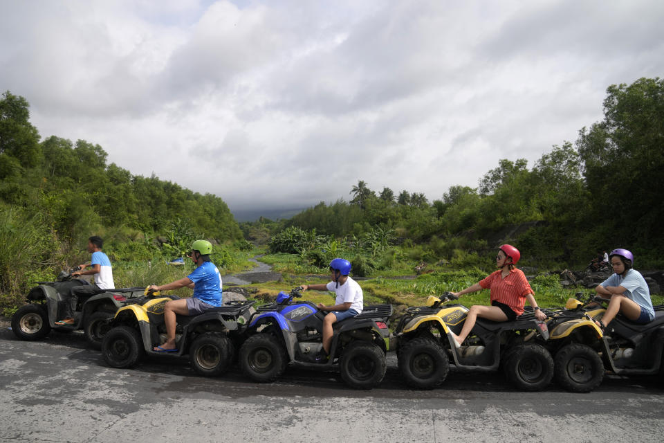 Tourists ride ATV's near Mayon Volcano, hidden in clouds, in Daraga, Albay province, northeastern Philippines on Sunday, June 11, 2023. Thousands of villagers have been forced to leave rural communities within a 6-kilometer radius of Mayon volcano's crater in Albay province. (AP Photo/Aaron Favila)