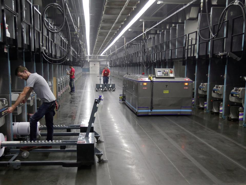 Workers exchange spools of thread as a robot picks up thread made from recycled plastic bottles at the Repreve Bottle Processing Center, part of the Unifi textile company in Yadkinville, N.C., Friday, Oct. 21, 2016. America has lost more than 7 million factory jobs since manufacturing employment peaked in 1979. Yet American factory production, minus raw materials and some other costs, more than doubled over the same span to $1.91 trillion last year, according to the Commerce Department, which uses 2009 dollars to adjust for inflation. Thatâ€™s a notch below the record set on the eve of the Great Recession in 2007. And it makes U.S. manufacturers No. 2 in the world behind China. ()