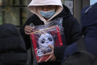 A man holds the Olympic mascot Bing Dwen Dwen doll which he purchased form a store selling 2022 Winter Olympics memorabilia in Beijing, Monday, Feb. 7, 2022. The race is on to snap up scarce 2022 Winter Olympics souvenirs. Dolls of mascot Bing Dwen Dwen, a panda in a winter coat, sold out after buyers waited in line overnight in freezing weather. (AP Photo/Andy Wong)