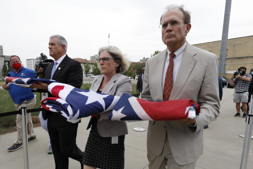 Speaker Philip Gunn, R-Clinton, left, Lt. Gov. Delbert Hosemann, right, and Mississippi Department of Archives and History Director Katherine Blount, center, carry the former Mississippi state flags to the Two Mississippi Museums during its retirement ceremony in Jackson, Miss., Wednesday, July 1, 2020. The flags had flown over the Capitol grounds during the day. The banner was the last state flag with the Confederate battle emblem on it. (AP Photo/Rogelio V. Solis)