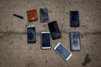 Wet phones and other items are placed on the ground by police officers as they inspect a boat where 15 Malians were found dead adrift in the Atlantic on Thursday, Aug. 20, 2020 in Gran Canaria island, Spain. The 15 lifeless men were spotted inside a boat on August 19 by a Spanish plane 80 nautical miles (148 kilometers, 92 miles) from the island of Gran Canaria. Police collected what was left behind as evidence: a wallet, a dozen cell phones, windbreakers and waterproof boots. (AP Photo/Emilio Morenatti)