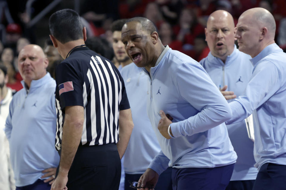 North Carolina coach Hubert Davis, center, argues a call with an official during the first half of the team's NCAA college basketball game against North Carolina State, Sunday, Feb. 19, 2023, in Raleigh, N.C. (AP Photo/Chris Seward)