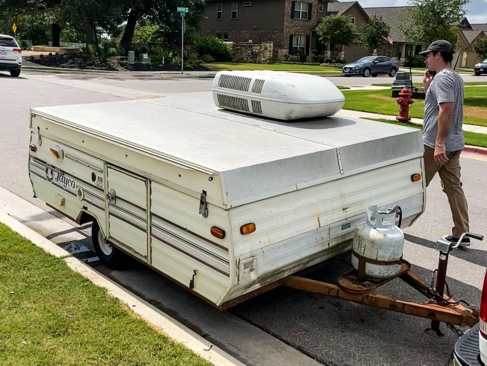 The pop-up camper outside of a house in a residential neighborhood while down