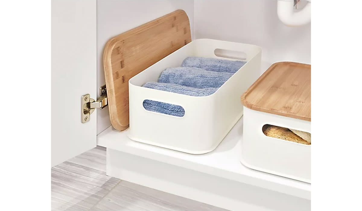 Two bamboo-lidded white storage bins beneath a sink
