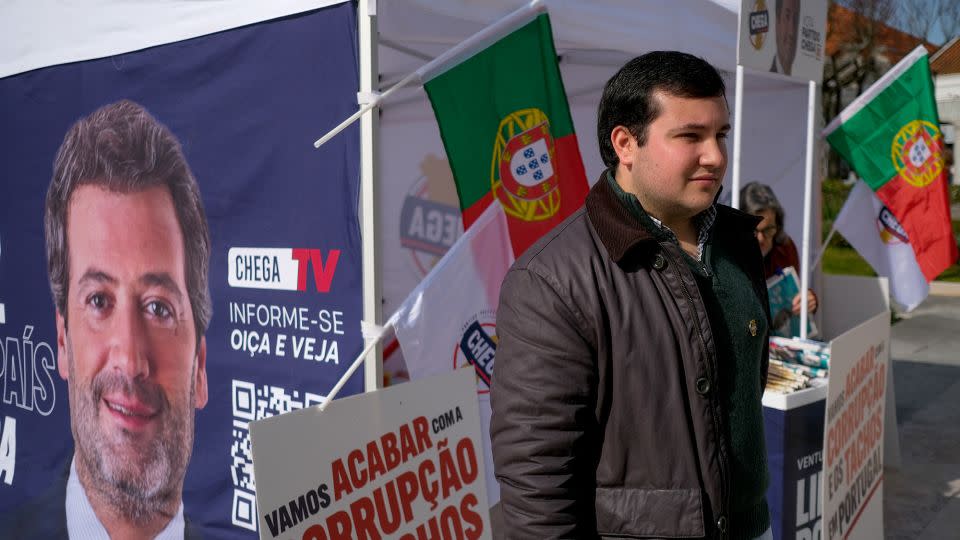 Afonso Mestre, 20, stands next to a Chega party campaign booth. - Vasco Cotovio/CNN