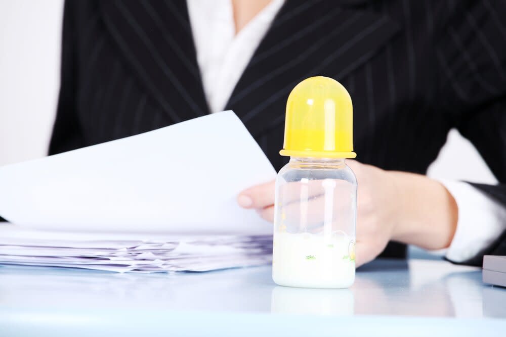 Closeup of mother in suit with baby bottle