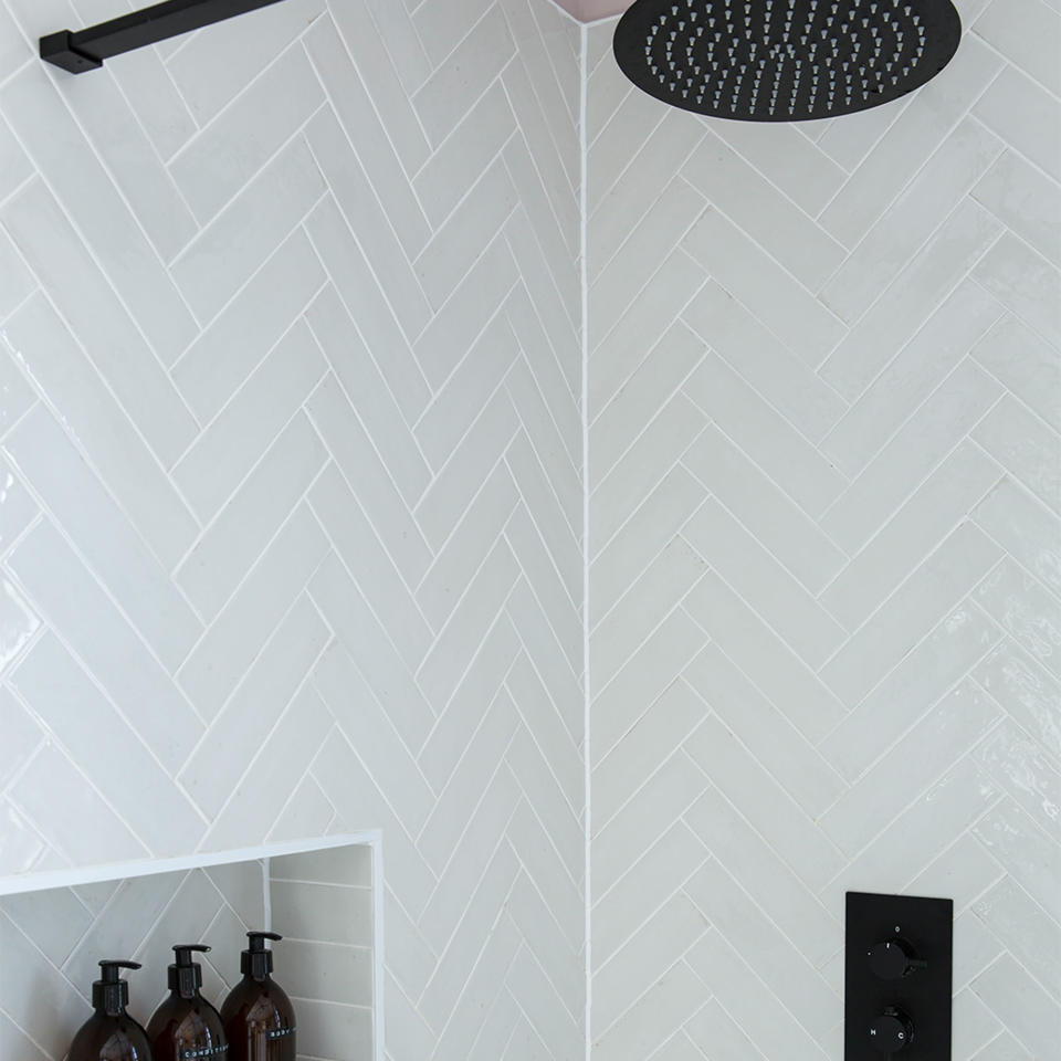 shower with marble herringbone tiles and black shower head