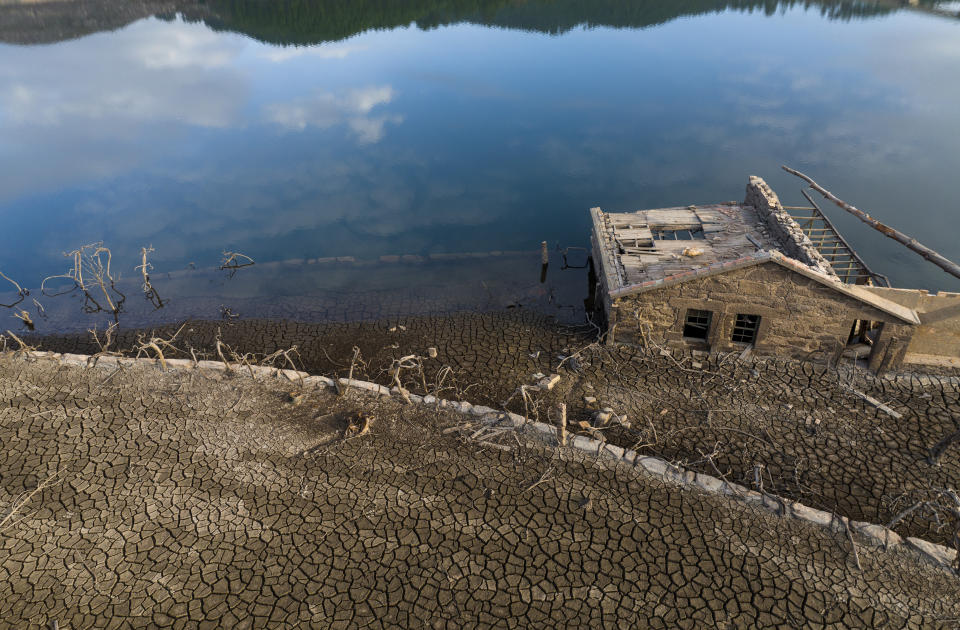 An old house, submerged three decades ago when a hydropower dam flooded the valley, is photographed emerged due to drought at the Lindoso reservoir, in northwestern Spain, Saturday, Feb. 12, 2022. With rainfall levels this winter at one-third of the average in recent years, large swaths of Spain are experiencing extreme or prolonged drought. (AP Photo/Emilio Morenatti)