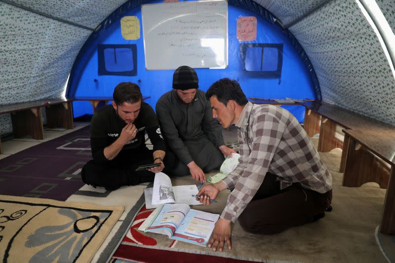 Ahmed Hadaja watches with other teachers video lessons for students in Atmeh camp