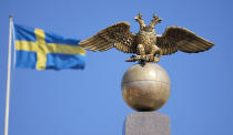 FILE - A Russian Imperial double-headed eagle is seen in front of a Swedish flag on the Czarina's Stone in the Market Square, in Helsinki, Finland, Friday, May 13, 2022. Finland and Sweden have signaled their intention to join NATO over Russia’s war in Ukraine and things will move fast once they formally apply for membership in the world’s biggest security alliance. Russian President Vladimir Putin has already made clear that there would be consequences if the two Nordic countries join. (AP Photo/Martin Meissner, File)