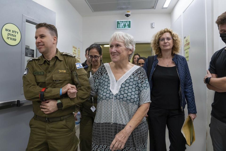 Margalit Mozes, a released Israeli hostage, walks with an Israeli soldier shortly after her arrival in Israel on Friday, Nov. 24, 2023. A four-day cease-fire in the Israel-Hamas war began in Gaza on Friday with an exchange of hostages and prisoners. (IDF via AP)