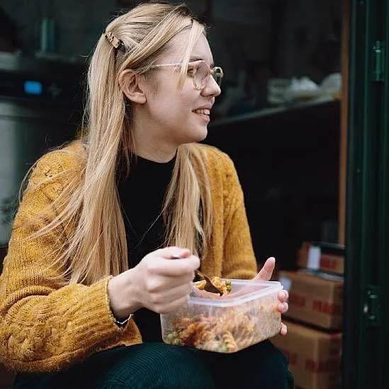 Una joven comiendo pasta de un tupper