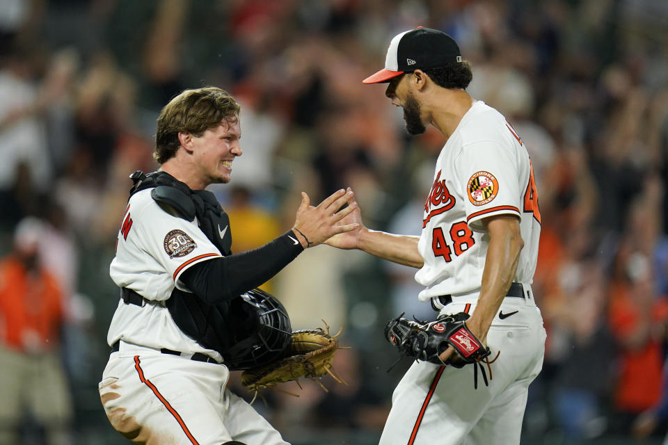 Baltimore Orioles catcher Adley Rutschman, left, and relief pitcher Jorge Lopez react after a baseball game against the Tampa Bay Rays, Tuesday, July 26, 2022, in Baltimore. The Orioles won 5-3. (AP Photo/Julio Cortez)