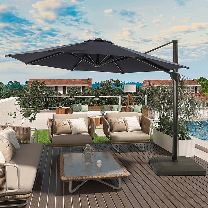 A cantilevering umbrella shading patio furniture by a pool