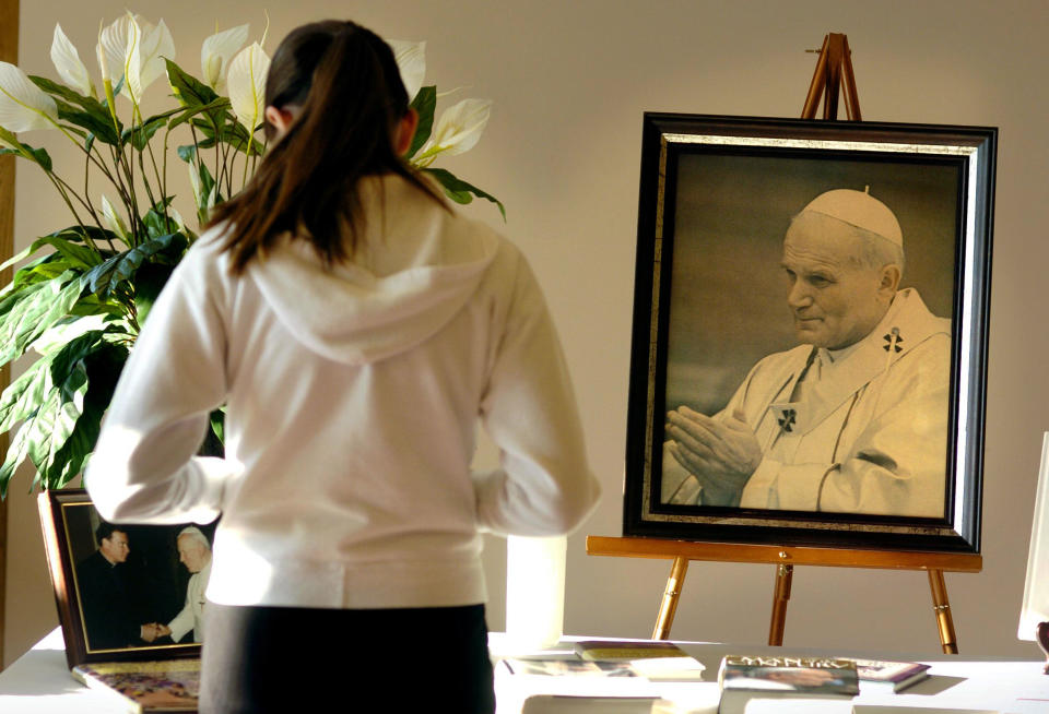 FILE - St. Maria Goretti parishoner Anna Buss, 10, pauses in front of a shrine to Pope John Paul II before Mass Saturday, April 2, 2005, in Madison, Wis. (John Maniaci/Wisconsin State Journal via AP, File)