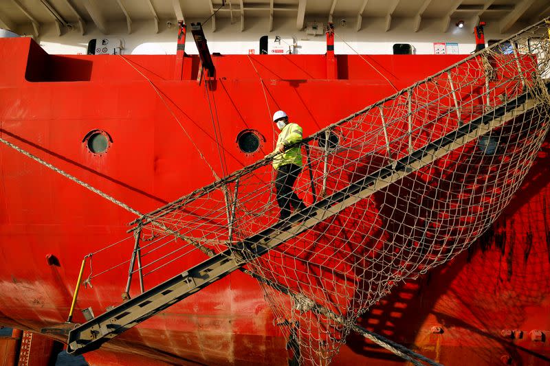 A dockworker wearing a mask walks down steps near a vessel at the port in Ashdod, Israel