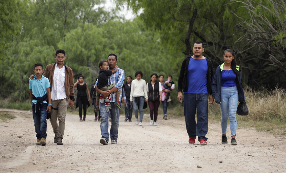 Familias de migrantes que acaban de cruzar ilegalmente el río Bravo caminan por una carretera de tierra cerca de McAllen, Texas, esperando ser capturadas por el servicio de inmigración. La idea es que se empiece a procesar sus casos y ser liberados. (AP Photo/Eric Gay)