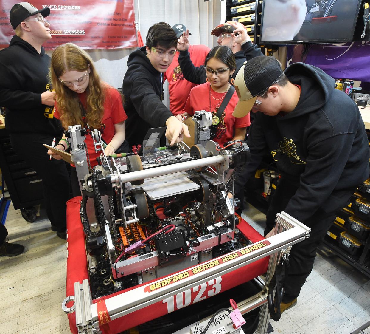 Bedford Express FRC Team #1023 robotics team members building lead Brandon Fisher (behind), Brenyn Hebert, electronic lead and chassis driver Eric Koenemann, Addison Huerta and BX engineer captain Gabriel Tegtmeyer look over the robot in the DTE Foundation pit area before the FIRST in Michigan State Championship 2024 at Saginaw Valley State University April 5, 2023.