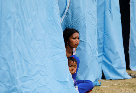 A woman and child sit in a tent at a temporary evacuation center for people living near Mount Agung, a volcano on the highest alert level, outside a sports arena in Klungkung, on the resort island of Bali, Indonesia, September 24, 2017. REUTERS/Darren Whiteside