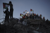 Protesters wave Palestinian flags as they stand atop the rubble of a building destroyed by an Israeli airstrike last month, during a protest against a march by Jewish ultranationalists through east Jerusalem, in Beit Lahia, northern Gaza Strip, Tuesday, June 15, 2021. (AP Photo/Felipe Dana)