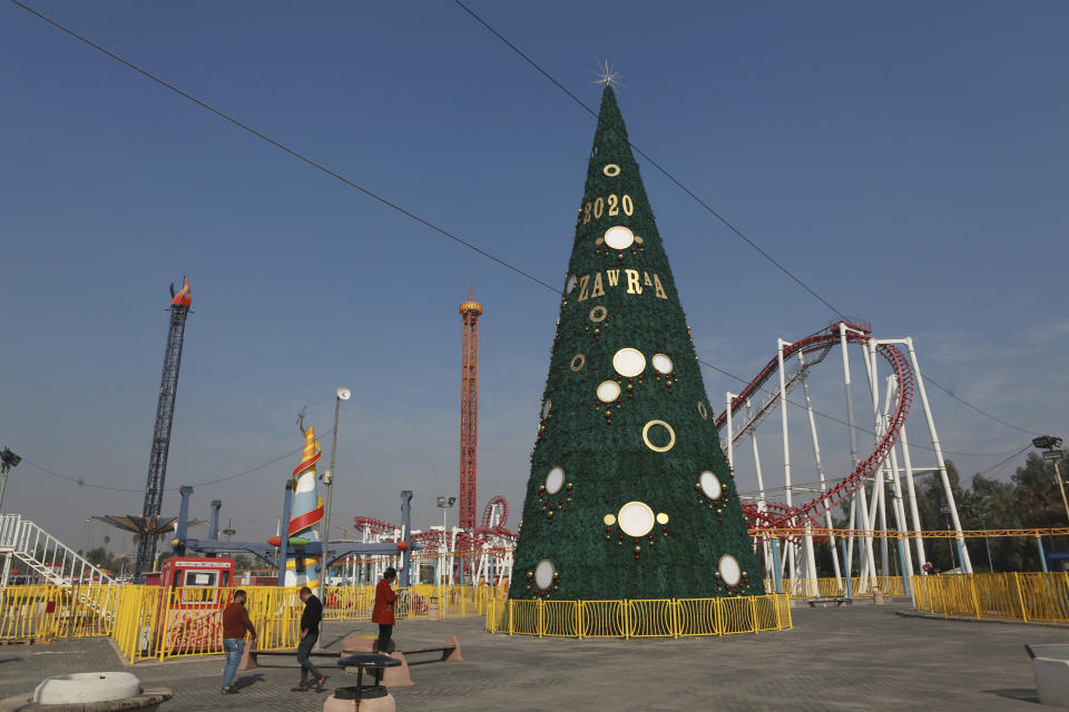 In this Thursday, Dec. 5, 2019 photo, people walk near a large Christmas tree in al-Zawra Park, Baghdad, Iraq. Leaders of Iraq's Christians unanimously cancelled Christmas-related celebrations in solidarity with the protest movement - but the aims of their stance go deeper than tinsel and fairy lights. In the slogans calling for a united Iraq, Christians see hope for much needed change from a sectarian system that has long marginalized them. (AP Photo/Khalid Mohammed)