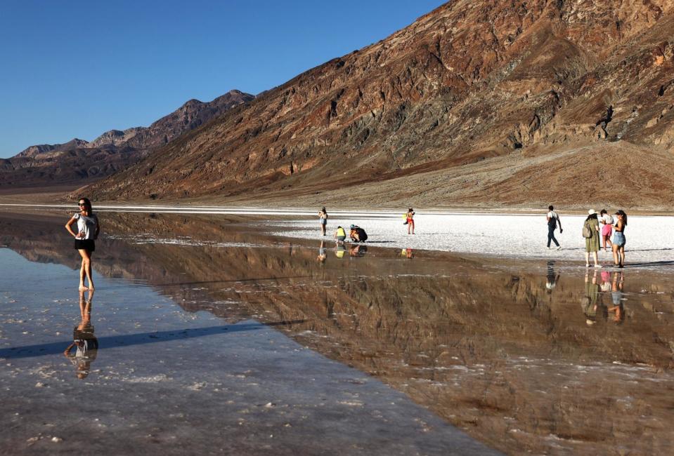 PHOTO: Visitors gather at the sprawling temporary lake at Badwater Basin salt flats, which was caused by flooding in August from Tropical Storm Hilary, at the recently reopened Death Valley National Park, Oct. 21, 2023. (Mario Tama/Getty Images)