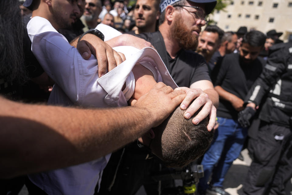 Israeli police detain a suspected attacker in an apparent car ramming that wounded three people on the eve of the Jewish holiday of Passover, in Jerusalem, Monday, April 22, 2024. Israeli police say a car slammed into pedestrians in Jerusalem on Monday, wounding three people lightly in an apparent attack. The three were injured when a car ran them over in the neighborhood of Romema, northeast of the city center. Police said two attackers exited the vehicle with a submachine gun and fled the scene. (AP Photo/Ohad Zwigenberg)