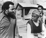 FILE - Former football great Jim Brown, left, President of the Black Economic Union, confers with Mrs. Anne Faulkner, 74, in her poor neighborhood at Holly Springs, Miss., Feb. 11, 1970. Brown led about 25 black athletes for the firsthand look at conditions his BEU hopes to improve. In background is Leroy Kelly of the Cleveland Browns. (AP Photo/File)