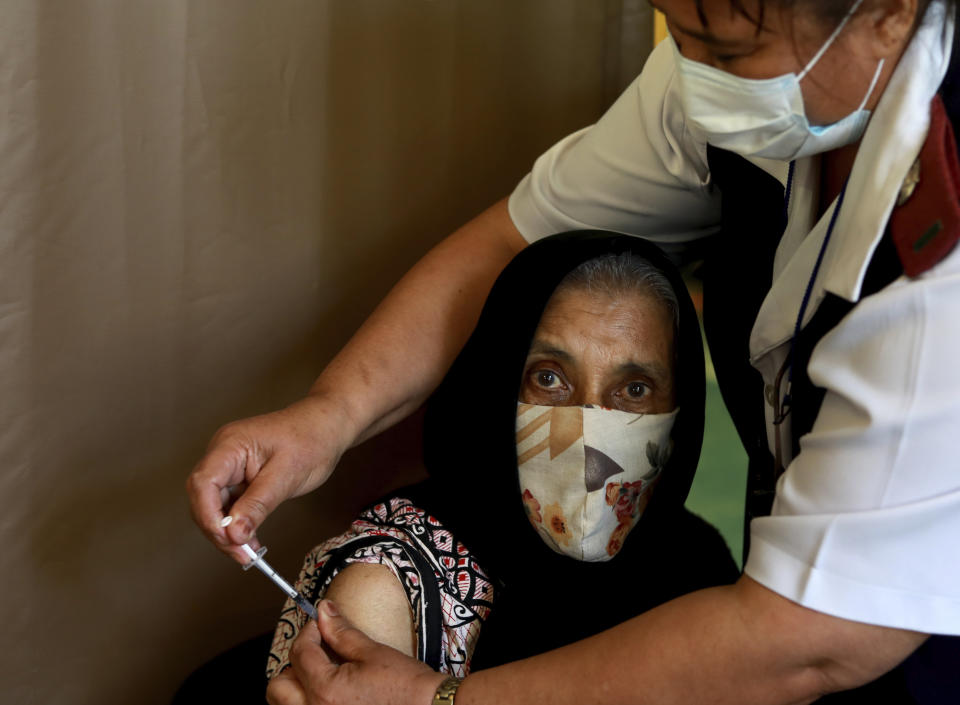 Seventy six year old Kaironesa Sheik Suleman Allie receives a first dose of the Pfizer COVID-19 vaccine from a health staff member, at a vaccination center, in Karl Bremer Hospital, in Cape Town, South Africa, Wednesday, May 26, 2021. South Africa is in a race against time to vaccinate as many people as possible with signs the virus may be surging again. (AP Photo/Nardus Engelbrecht)