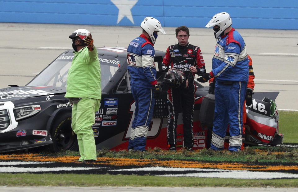 Officials tend to NASCAR Texas Trucks Series driver Christian Eckes (18) after he skidded out on the front stretch after contact from another vehicle during an auto race at Texas Motor Speedway in Fort Worth, Texas, Sunday, Oct. 25, 2020. (AP Photo/Richard W. Rodriguez)