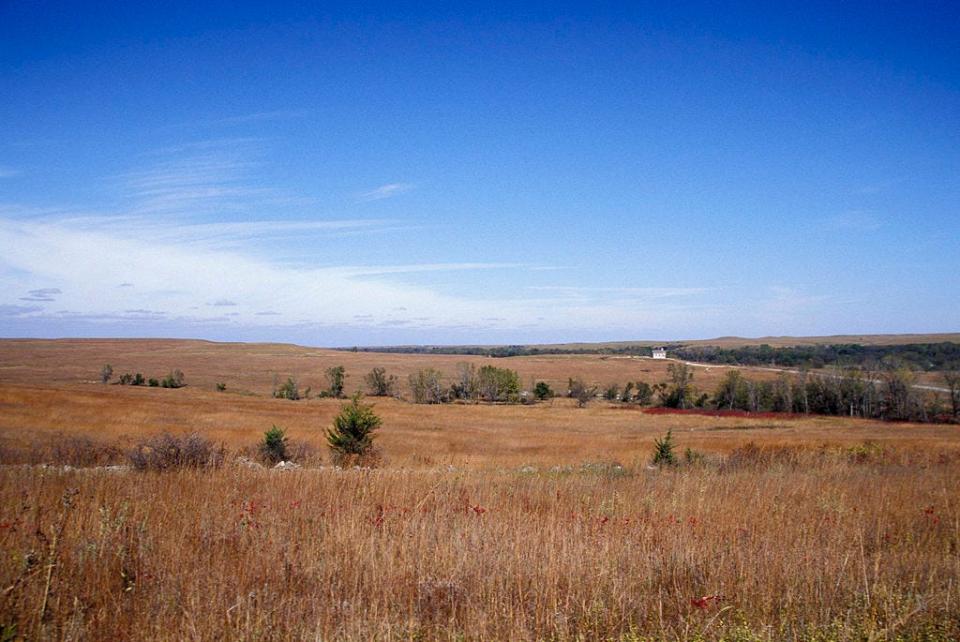 Large open fields of Tallgrass Prairie National Preserve with a schoolhouse in the distance.