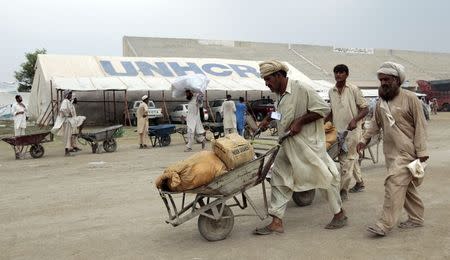 A labourer pushes a wheelbarrow containing aid for internally displaced people at a food distribution centre in a sports stadium in Bannu, in northwest Pakistan July 25, 2014. REUTERS/Caren Firouz