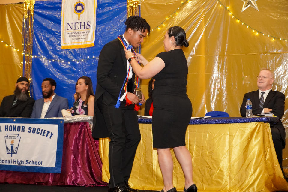 Dennis Barnes bows his head to receive an award, with members of a panel, one in Muslim skullcap and beard, sitting at a long table behind him draped in yellow and magenta satin.