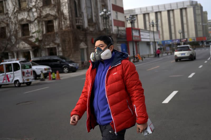 Un hombre con mascarilla camina por una calle, mientras el país es golpeado por un brote del novedoso coronavirus, en el distrito central de negocios de Pekín, China, el 18 de febrero de 2020