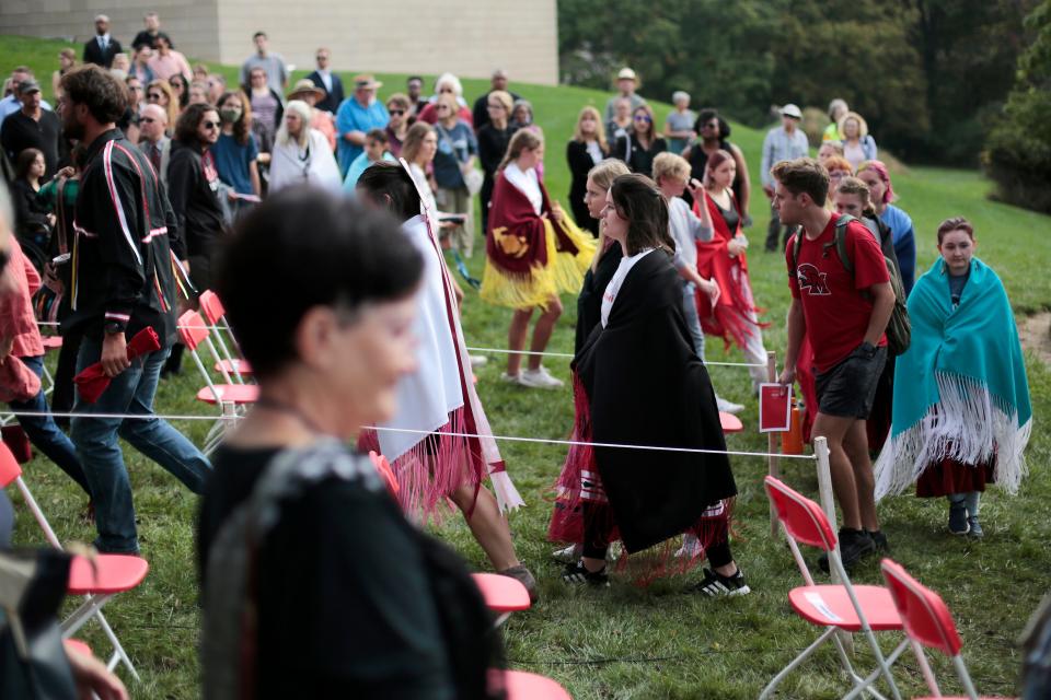 Students and other attendees walk in a line across campus along a trail marked by color fabric to honor the families forced from their homes during a Day of Reflection ceremony on the campus of Miami University in Oxford, Ohio, on Monday, Oct. 11, 2021. A ceremony was hosted to commemorate the 175th anniversary of the Myaamia Tribe that was forcibly removed from their land. 