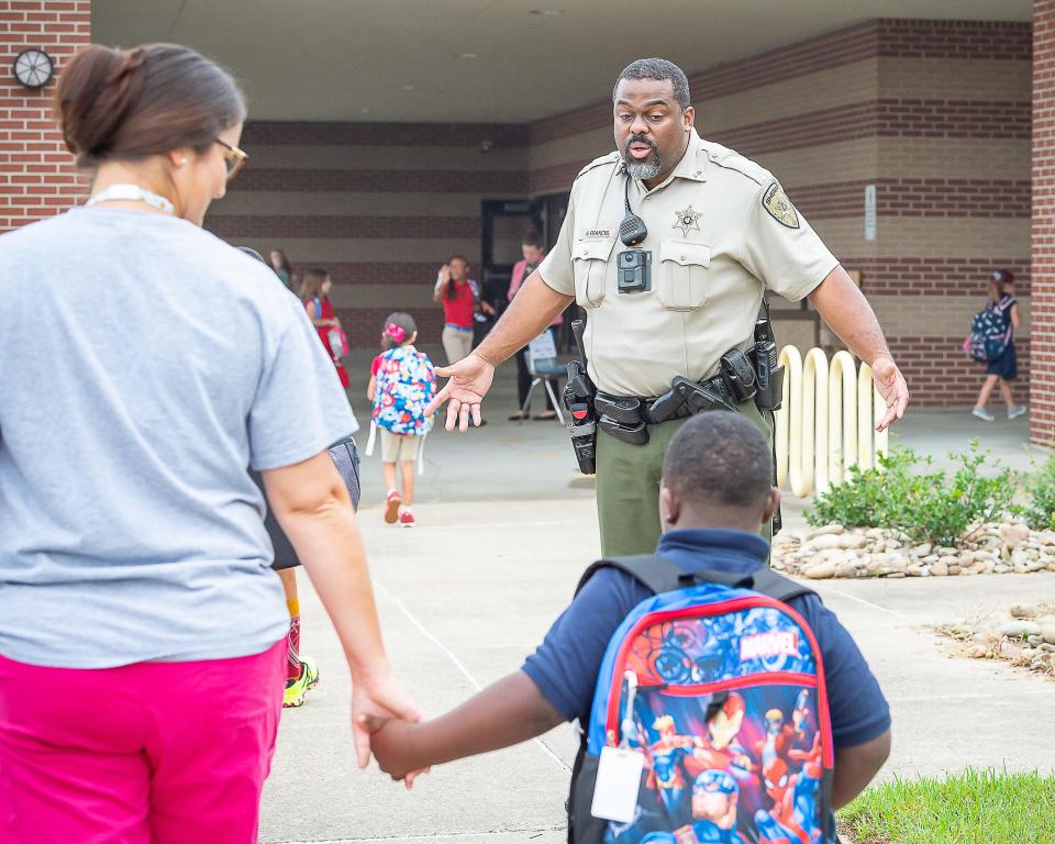 School resource officer Deputy Wilson Francis welcomes students as they arrive at J Wallace James Elementary for the first day of school Thursday, Aug. 11, 2022.