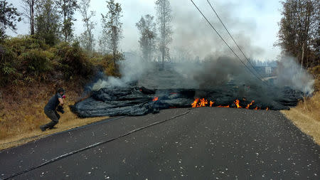 A lava flow is seen on a road in Pahoa, Hawaii, U.S., May 17, 2018 in this picture obtained from social media on May 18, 2018. KRIS BURMEISTER/via REUTERS