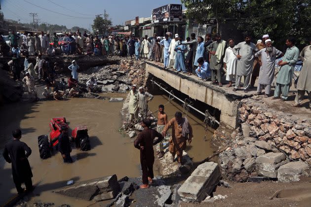 People stand around a washed-out road after heavy rains in Charsadda, Pakistan, on Aug. 30, 2022. (Photo: Muhammad Sajjad/AP)