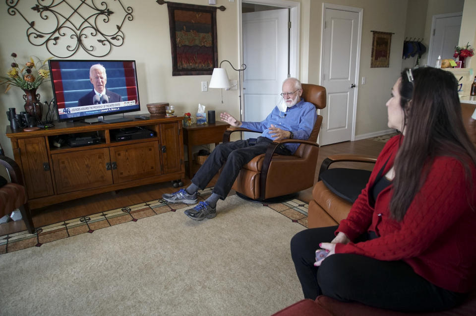 Democrat Jim Carpenter, left, and Republican Natalie Abbas watch the inauguration of President Joe Biden in Carpenter's apartment in Frederick, Md., on Wednesday, Jan. 20, 2021. The two are local ambassadors for a program designed to bridge the nation's extraordinary political divide. (AP Photo/Allen G. Breed)