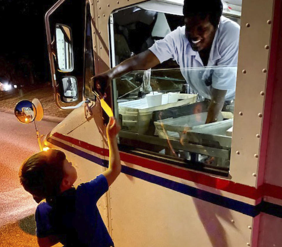 In this Nov. 12, 2020, photo provided by Bonnie Matthews, Chip Matthews, 6, hands postal worker, Tawanna Purter, a thank you card for the unexpected birthday gift she gave him a week earlier in Opelika, Ala. Matthews loves to get the mail, and on his birthday, Purter delivered his presents along with $2 from her own pocket. (Bonnie Matthews via AP)