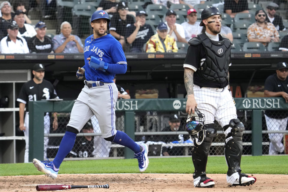 Toronto Blue Jays' George Springer, left, scores on a single by Daulton Varsho as Chicago White Sox catcher Yasmani Grandal looks to the field during the 11th inning in the first baseball game of a doubleheader Thursday, July 6, 2023, in Chicago. The Blue Jays won 6-2. (AP Photo/Nam Y. Huh)