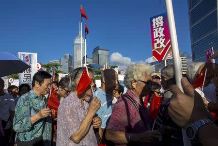 Pro-China supporters walking with Chinese flags as they attend a demonstration supporting a Beijing-backed electoral reform, outside Legislative Council in Hong Kong, China June 17, 2015. REUTERS/Tyrone Siu