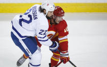 Toronto Maple Leafs' Zach Bogosian, left, checks Calgary Flames' Derek Ryan during the first period of an NHL hockey game, Tuesday, Jan. 26, 2021 in Calgary, Alberta. (Jeff McIntosh/The Canadian Press via AP)