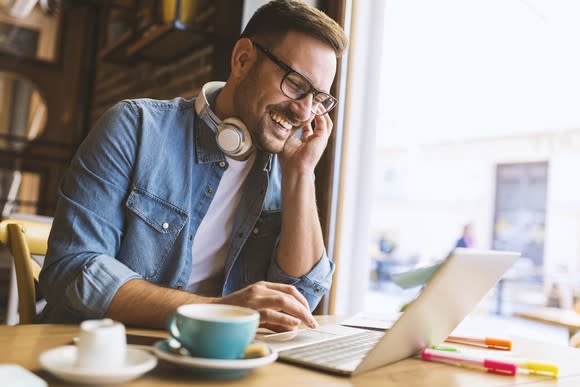 Man with headphones around his neck working at a laptop