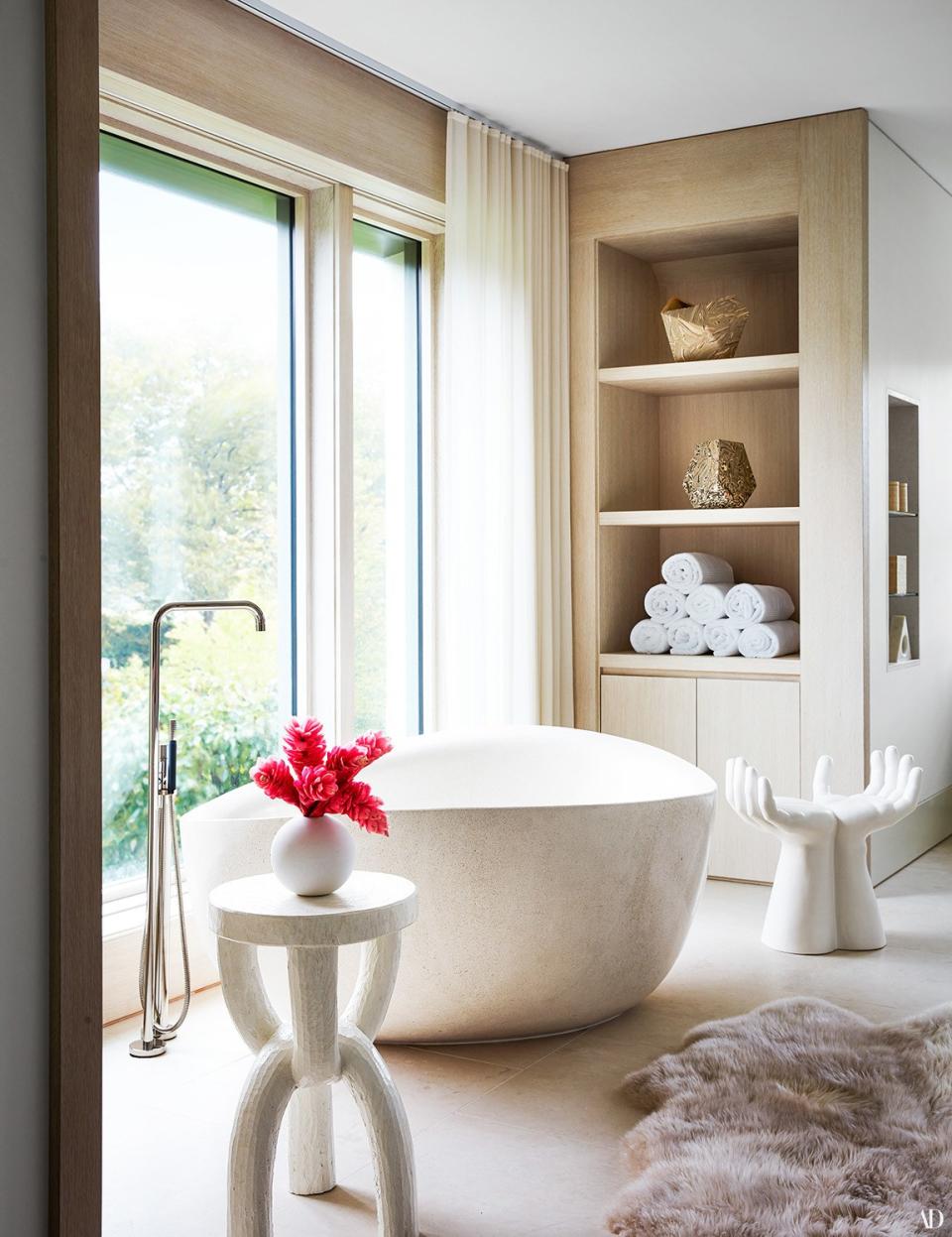 A chain stool by Clic (left) and hand stool by Studio A decorate the master bath. Tub filler by Vola; fur throw (on floor) from Roman and Williams Guild; vases (on shelves) by Cody Hoyt.