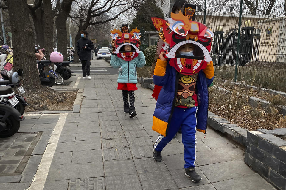 FILE - Children wearing cardboard lion dance masks walk along a street in Beijing on Jan. 13, 2023. China has announced its first overall population decline in recent years amid an aging society and plunging birthrate. (AP Photo/Mark Schiefelbein, File)