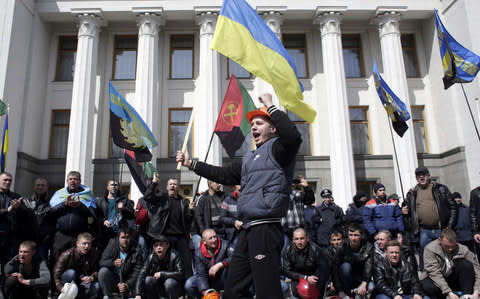 Ukrainian coal miners hold Ukrainian national flags as they protest outside the Ukrainian Parliament in Kiev - Credit: NATOLII STEPANOV/AFP/Getty Images