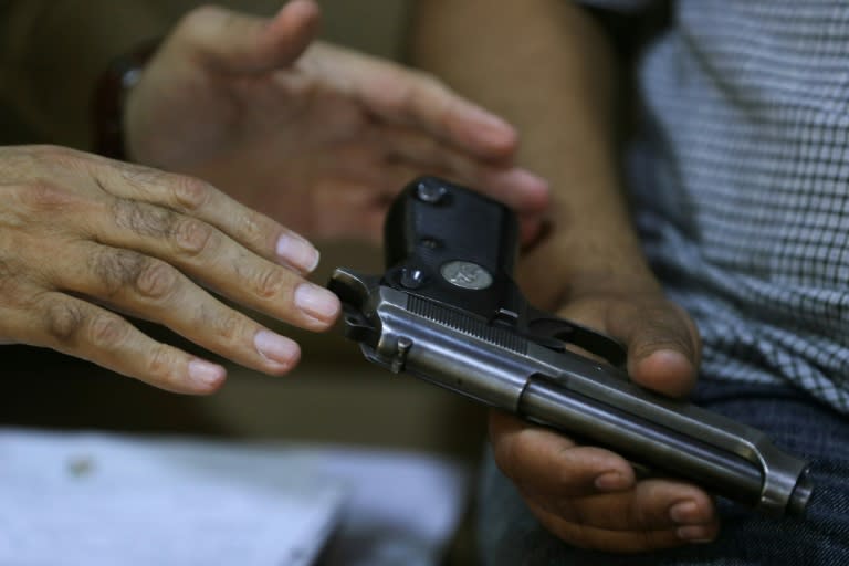 A police officer registers a weapon at a private home in Baghdad (AHMAD AL-RUBAYE)